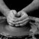 A black and white photo of someone shaping clay with their hands